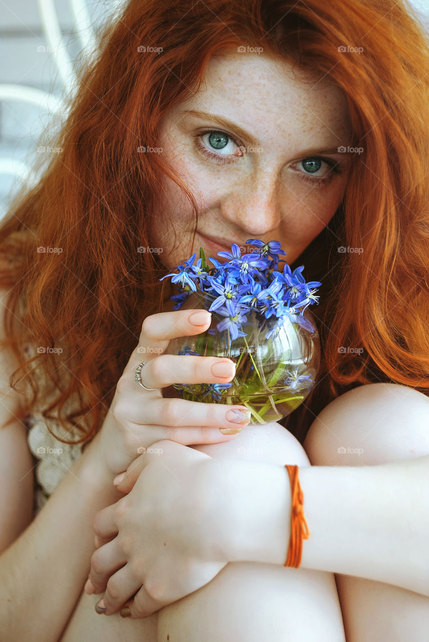 Portrait of beautiful young smiling woman with red hair and freckles in her face. Spring colors.
