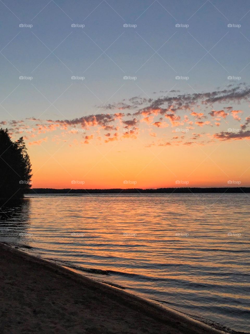 Side perspective view to the stunning magic dramatic sunset over the sea water surface with the sunlight reflection from the sand shore 