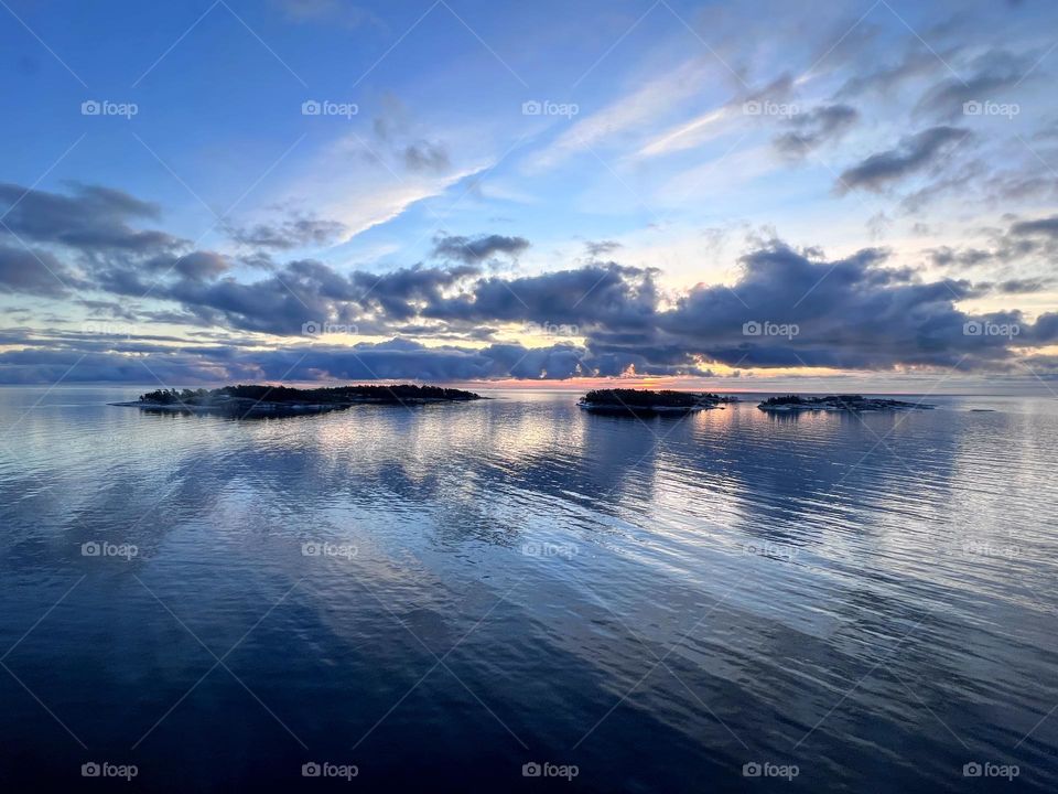 Amazing sunset scene over the Baltic Sea archipelago with clouds reflection in the still smooth water surface