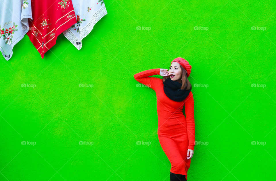 Girl in woolen cap posing against green wall