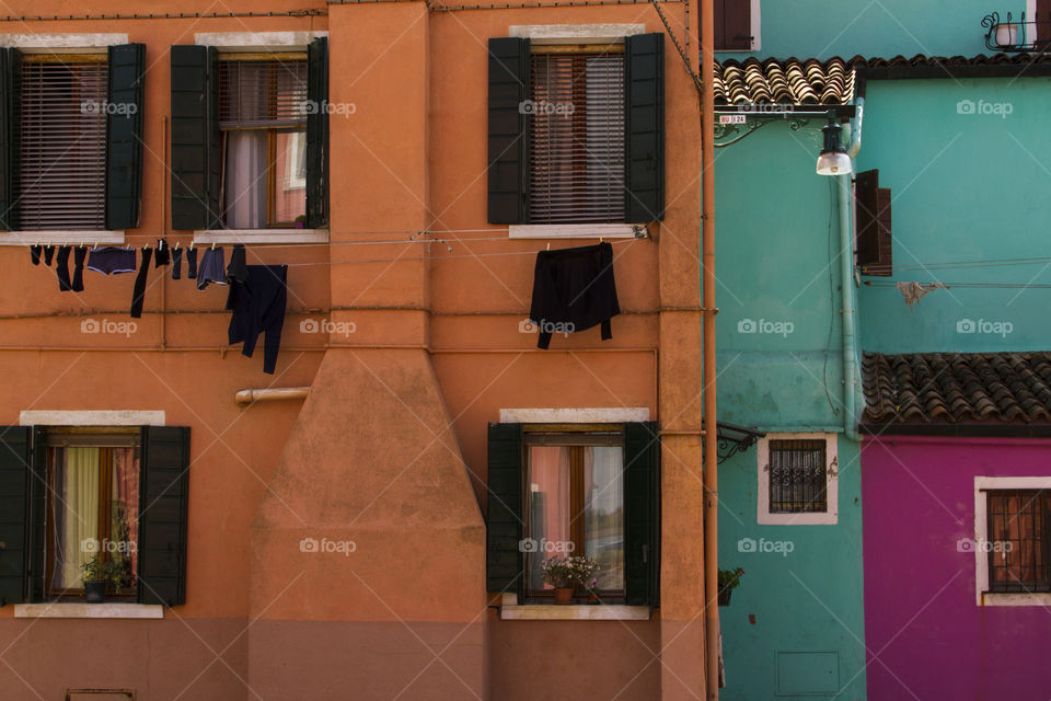 Laundry hanging outside of colorful houses in Burano