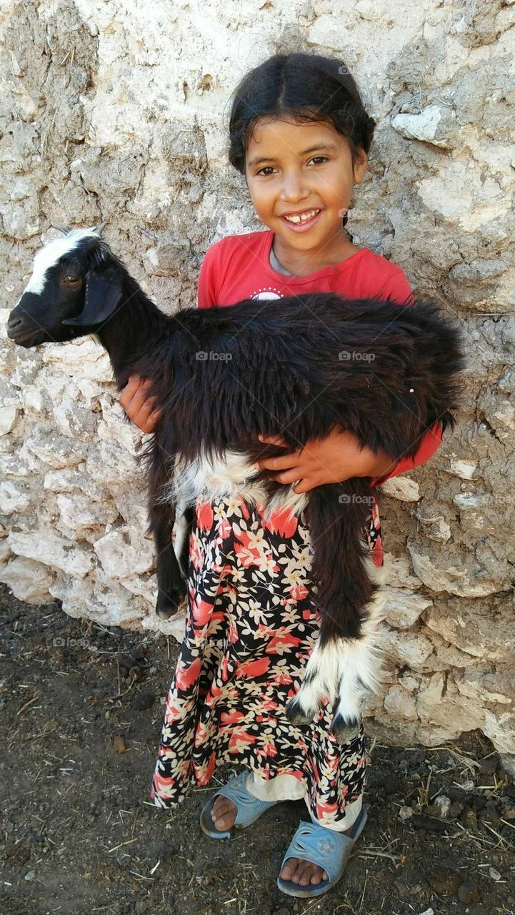 A beautiful girl holding a black goat.