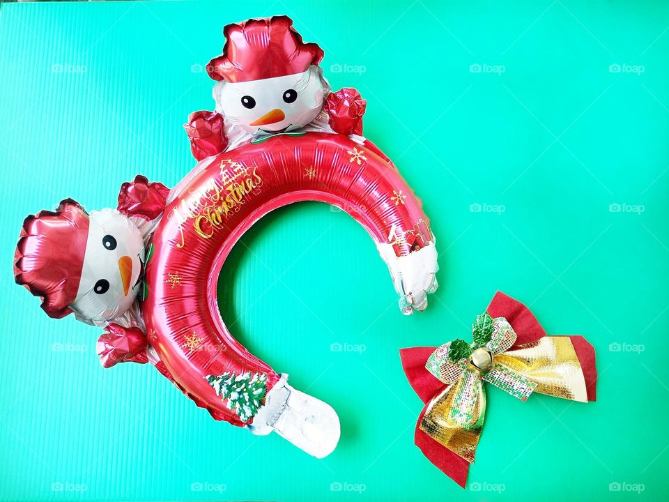 Snowman Christmas headband and Christmas bow on green background horizontal composition.