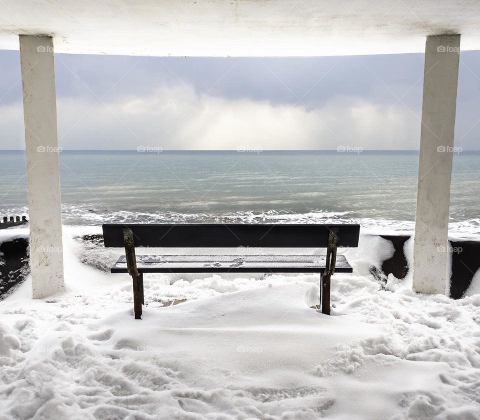 Wooden bench overlooking the English Channel at Hastings, in the snow