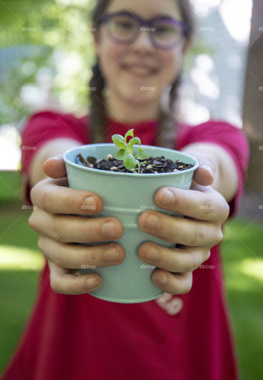 Girl holding a garden pot with a new seedling
