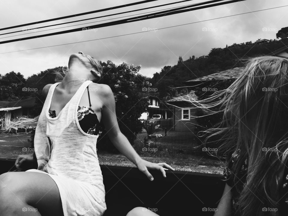 Girl feels free hanging out of the back of a truck with the wind in her hair.