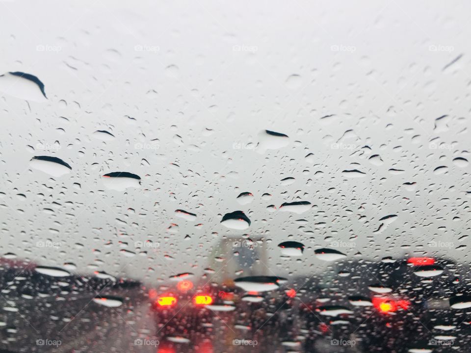 Raindrops on car windshield and traffic ahead 
