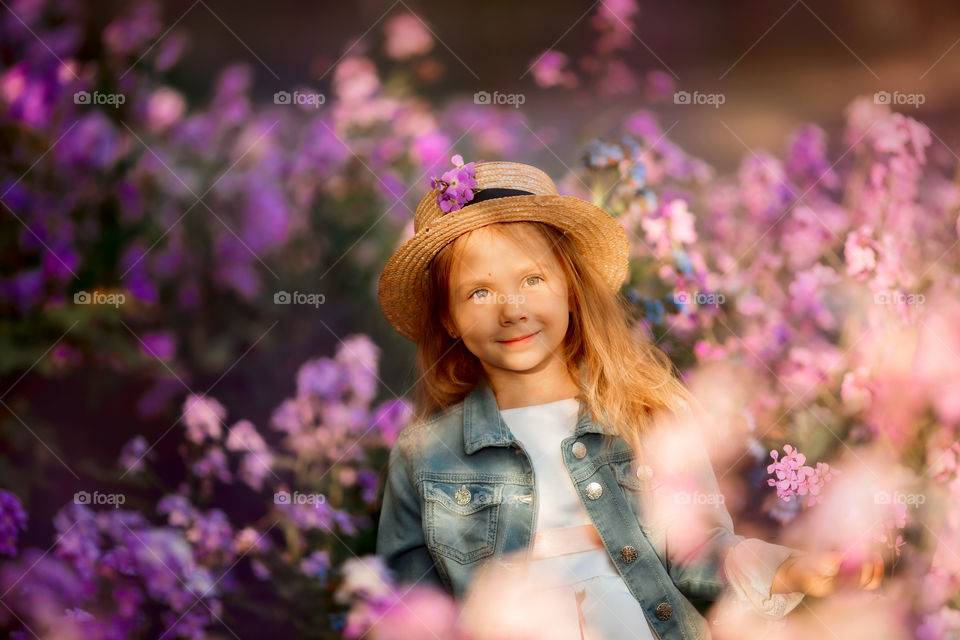 Cute little girl portrait in blossom meadow at sunset 