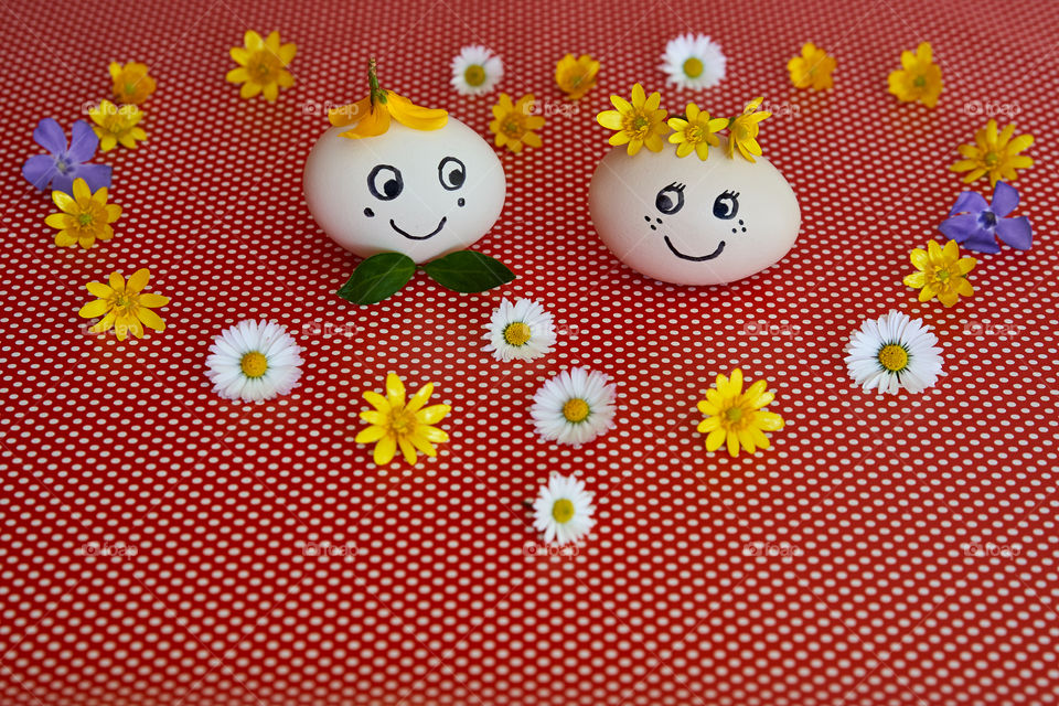 Easter.  Decorated Easter eggs with the funny smiling faces among the spring flowers on bright background 