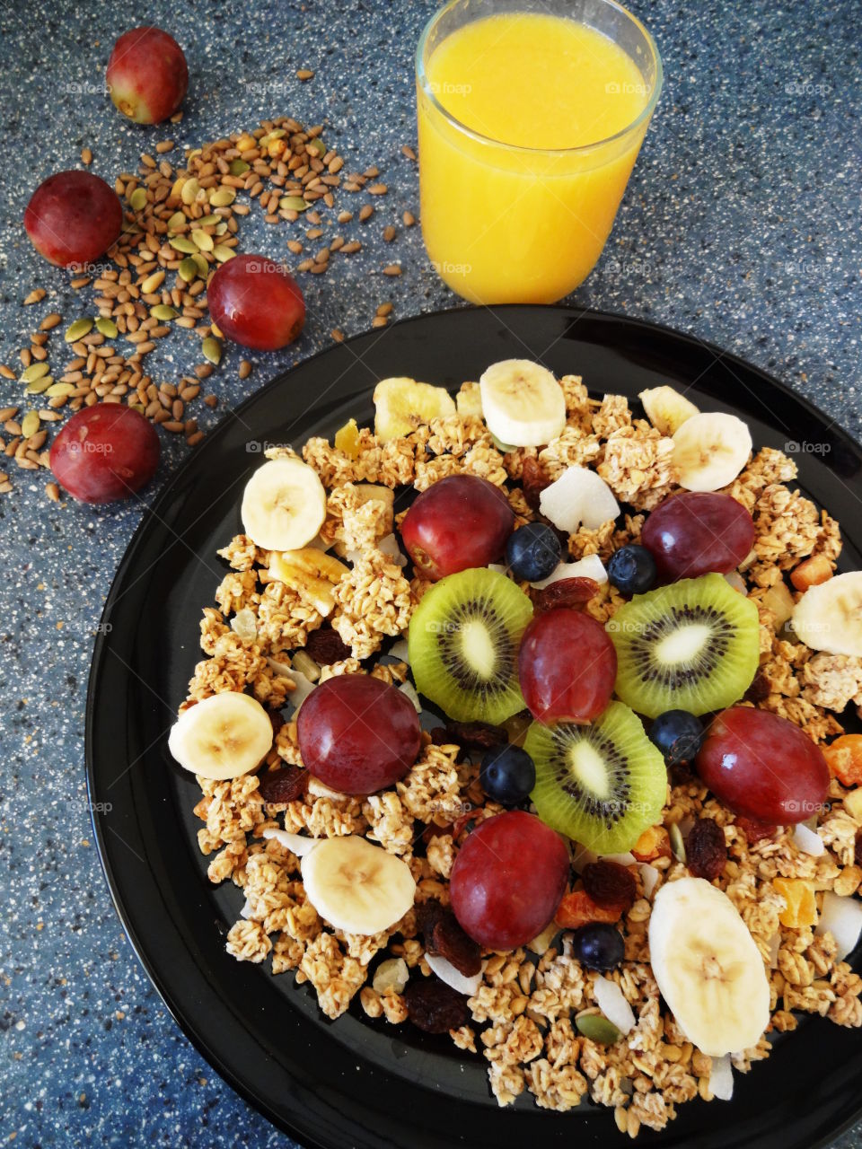 Healthy breakfast of crunchy flakes kiwi, banana, grapes, berries, raisins and fresh orange juicy drink