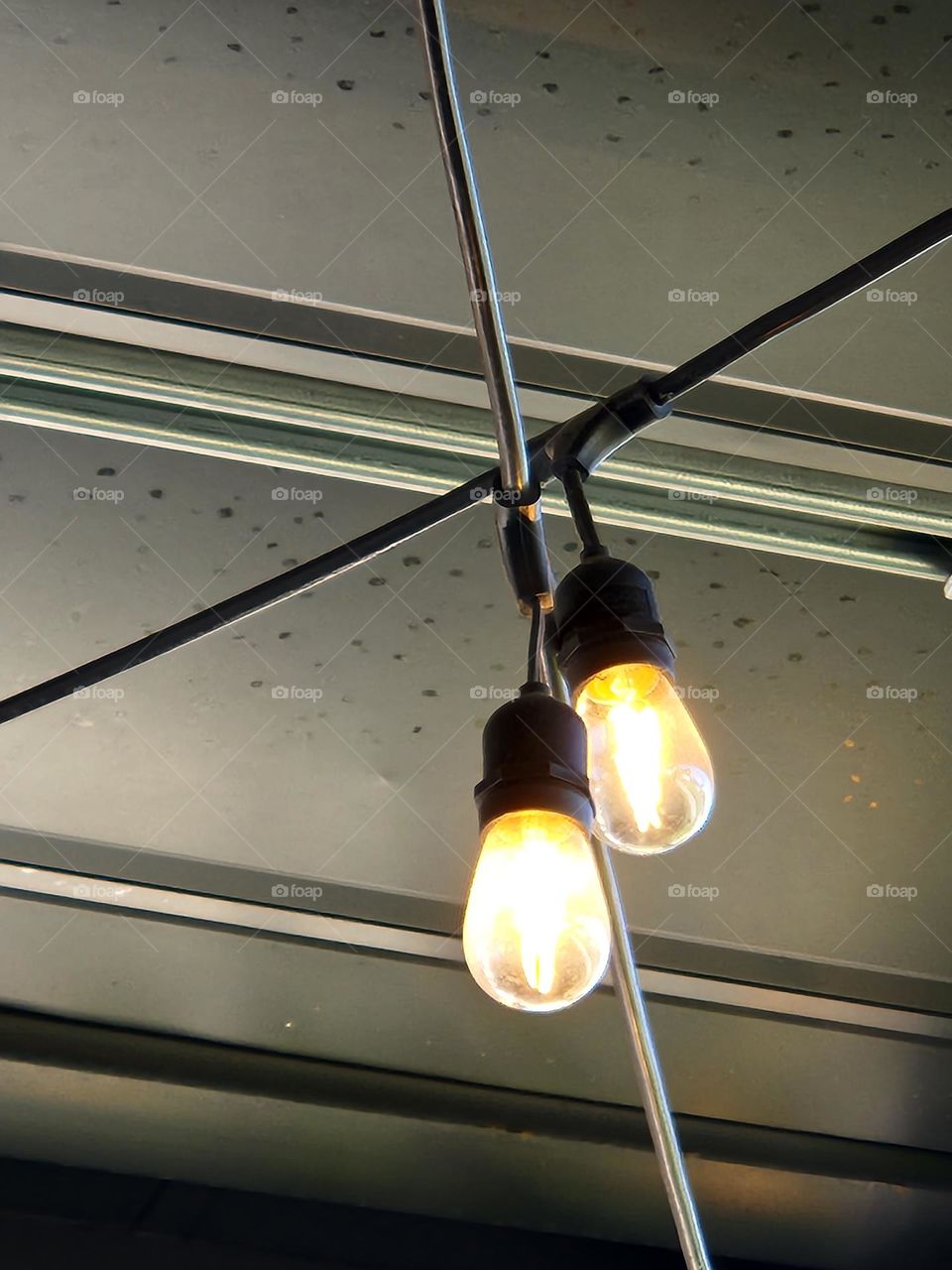 close up of two bright light bulbs hanging from a restaurant ceiling