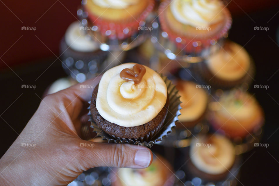 Hand holding a cupcake in front of the cupcake display