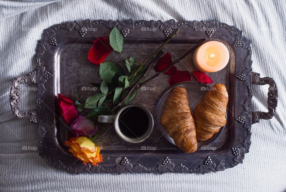 "Romantic breakfast of coffee and croissants with roses and candles.
Everything is placed on an antique silver tray above the bed."