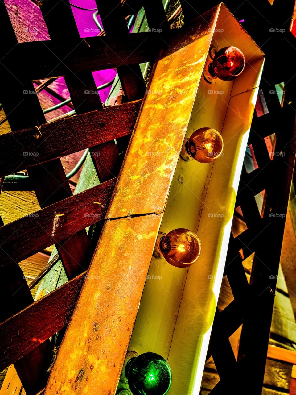 Part of a lighted metal sign of the letter I with colored lights illuminating in the night with the colors of reds, oranges, and yellows 