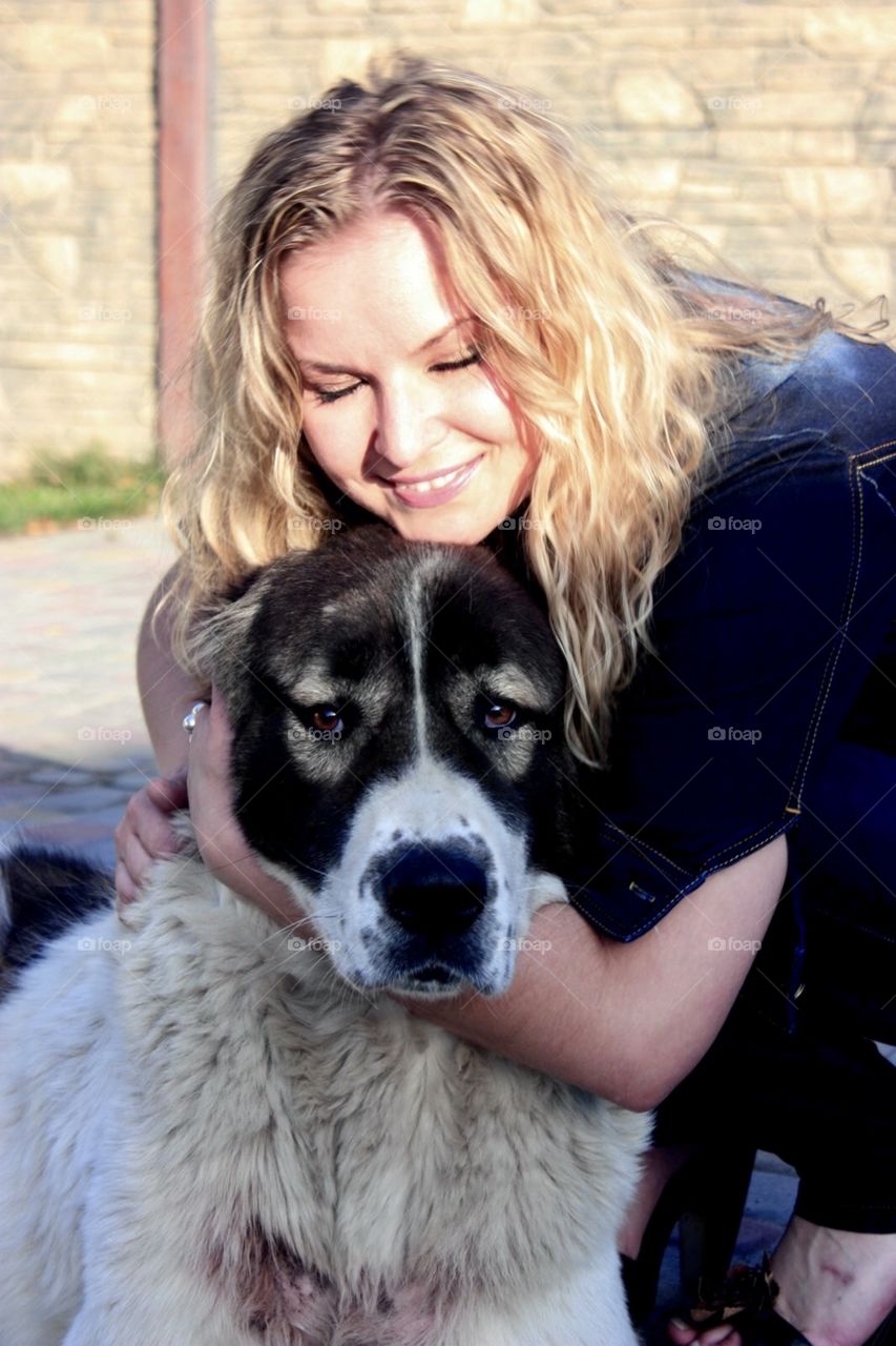 Smiling long haired girl hugging a big dog. 