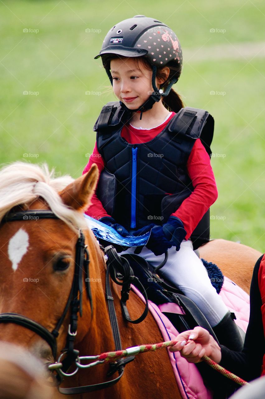 Girl wearing helmet riding on horse