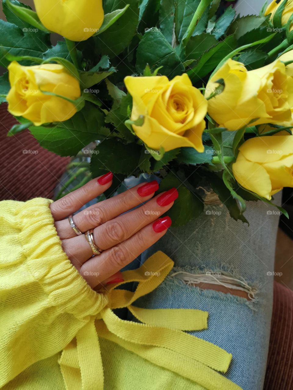 Red nail polish, red manicure. Yellow roses bouquet. Yellow jumper. 