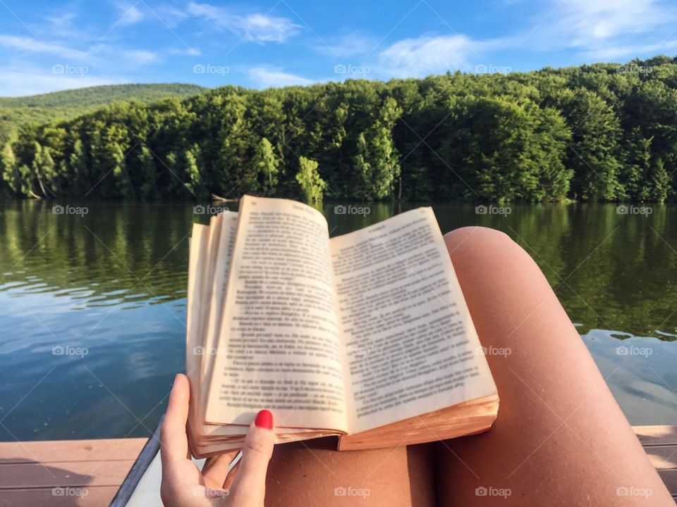 Woman reading by the lake in summer