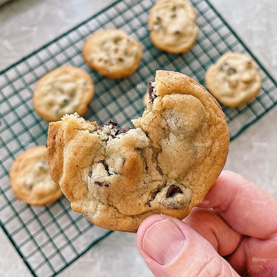 Smartphone food photo, woman holding chocolate chip cookie, hand eating cookie, bite taken out of chocolate chip cookie, freshly baked cookies, homemade cookies, delicious chocolate chip cookies