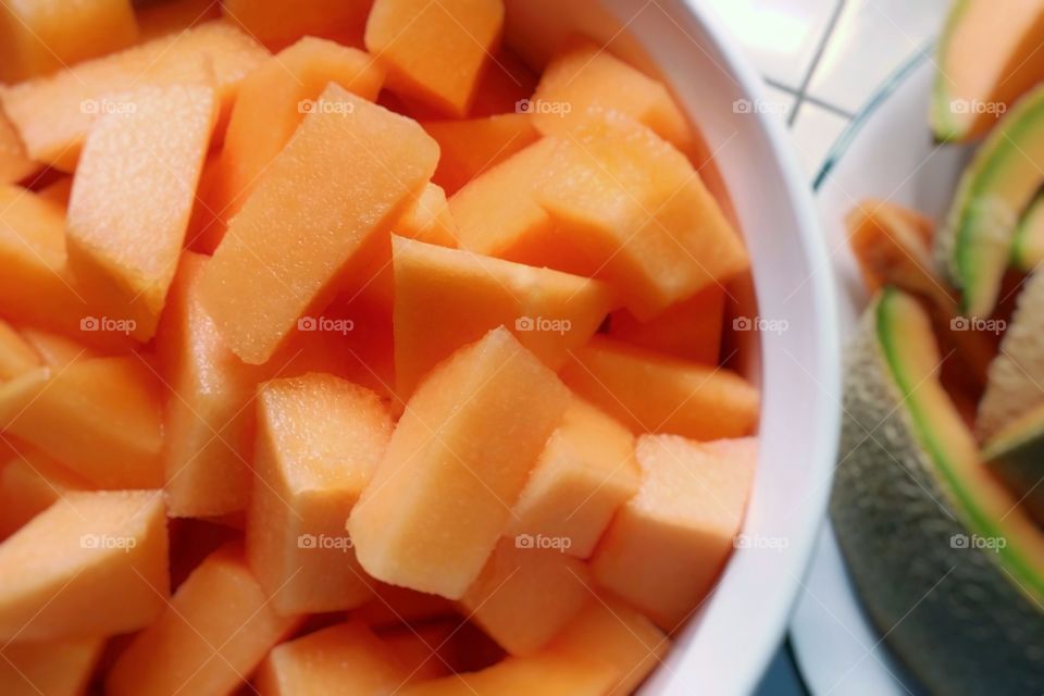 Summer in a bowl cut up pieces of cantaloupe with the peel in the background beautiful orange color