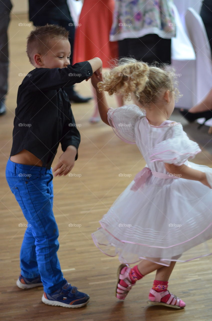 Cute girl and boy dancing on floor