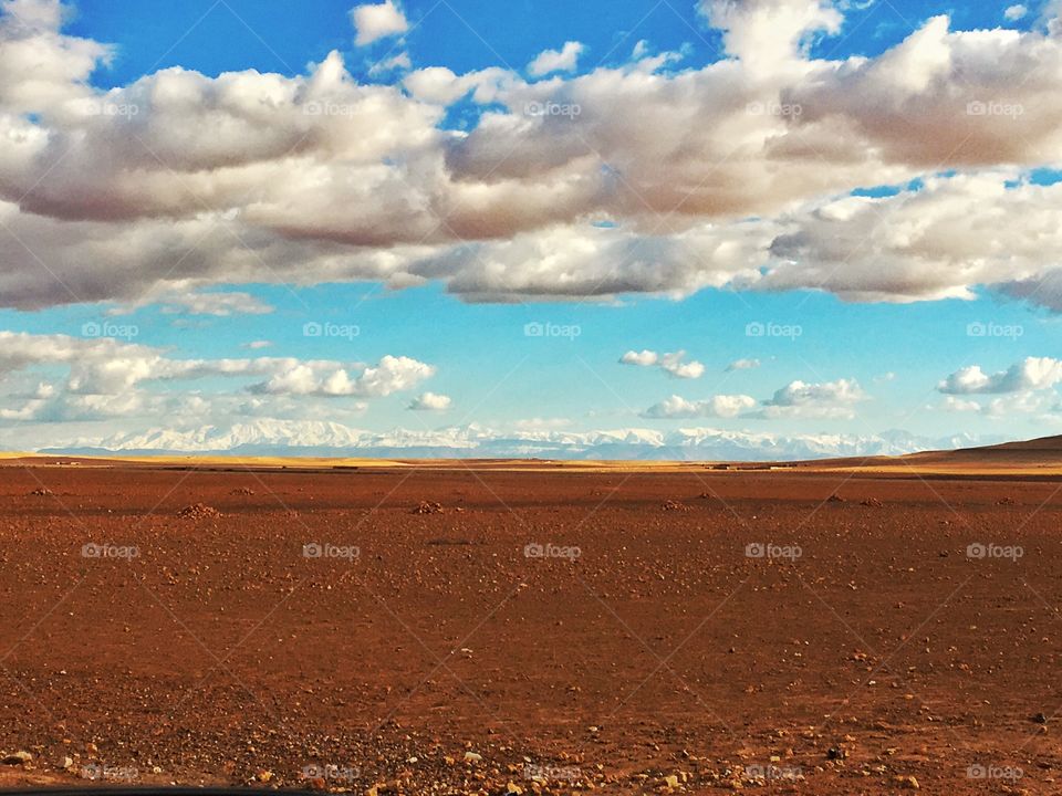 contrasting landscape with dry arid land and snow covered Atlas Mountains