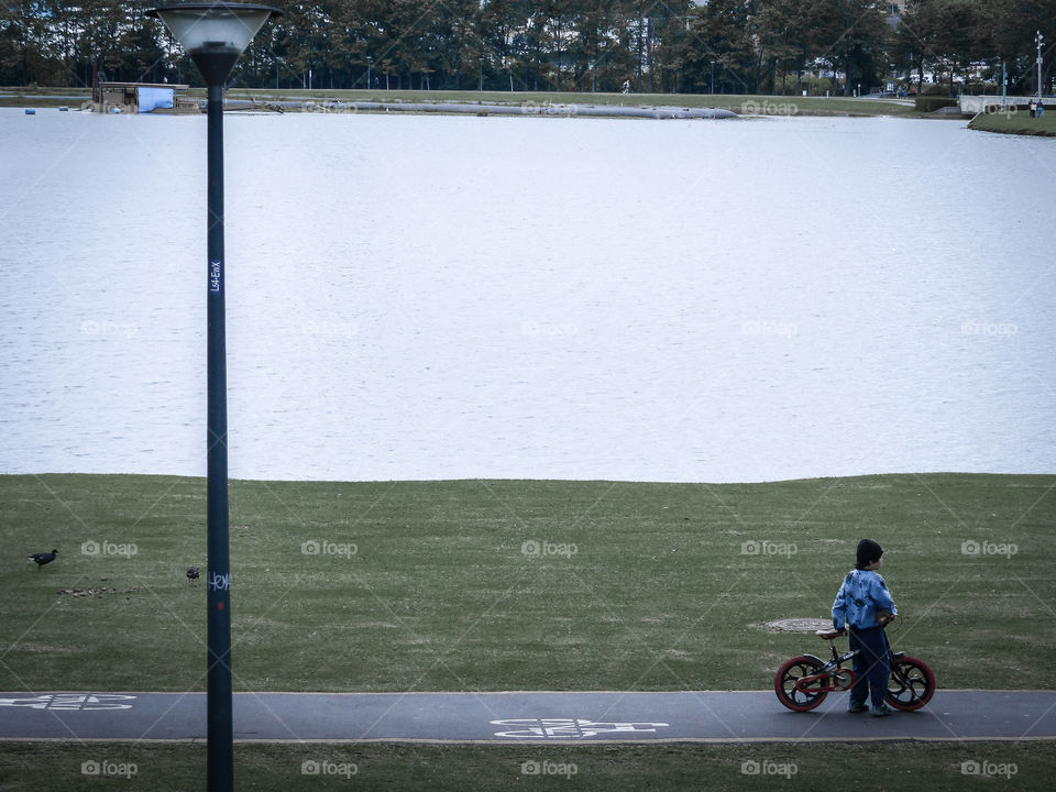 Little kid playing with his bicycle at the park (Barigui Park, in Curitiba, Brazil)