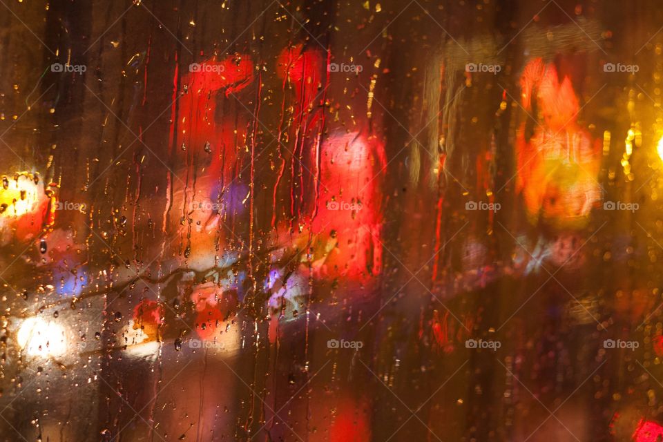 Red lights blurred behind wet window