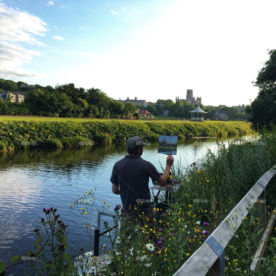 Artist at work painting a landscape of Durham Cathedral from the banks of the River Wear