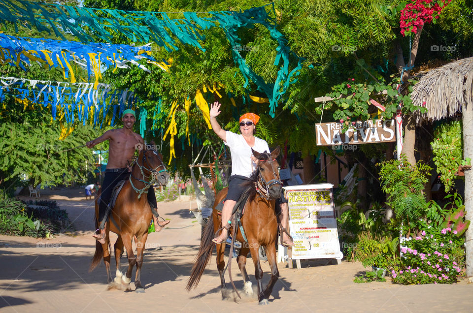 Woman and man riding horse in a village 