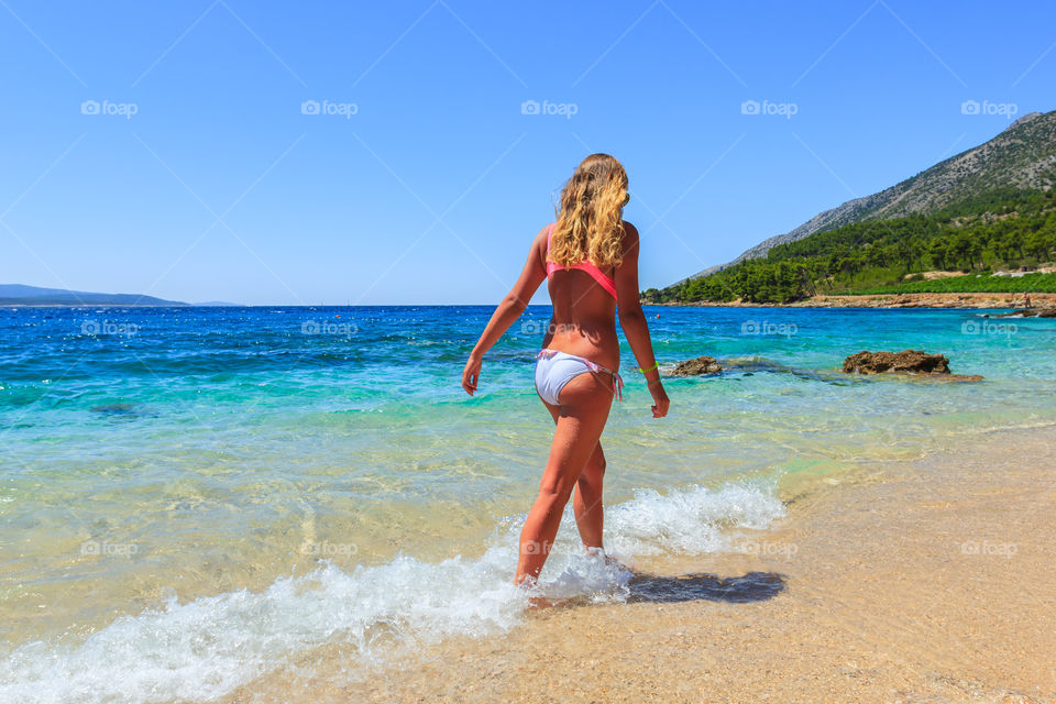 Beautiful young woman on beach. Beautiful young woman walking on beach, summertime, mediterranean sea, island Brac, Croatia.