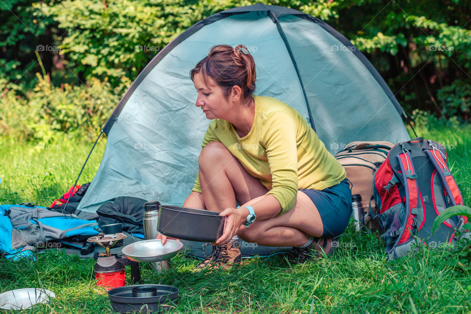 Spending a vacation on camping. Woman preparing a meal outdoor next to tent