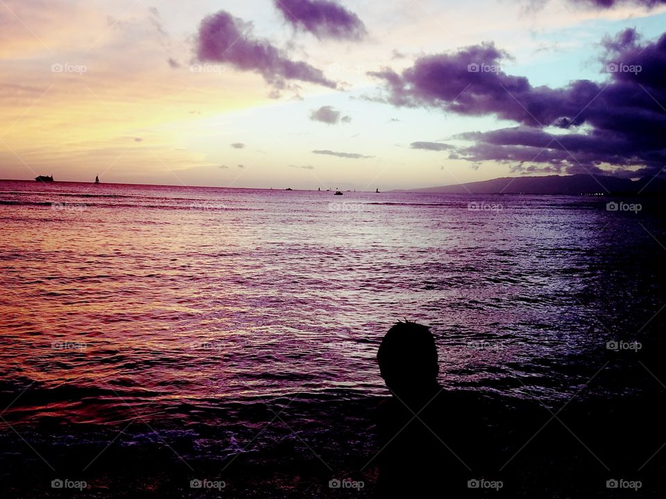 silhouette of young boy in front of sunset at Waikiki Beach
