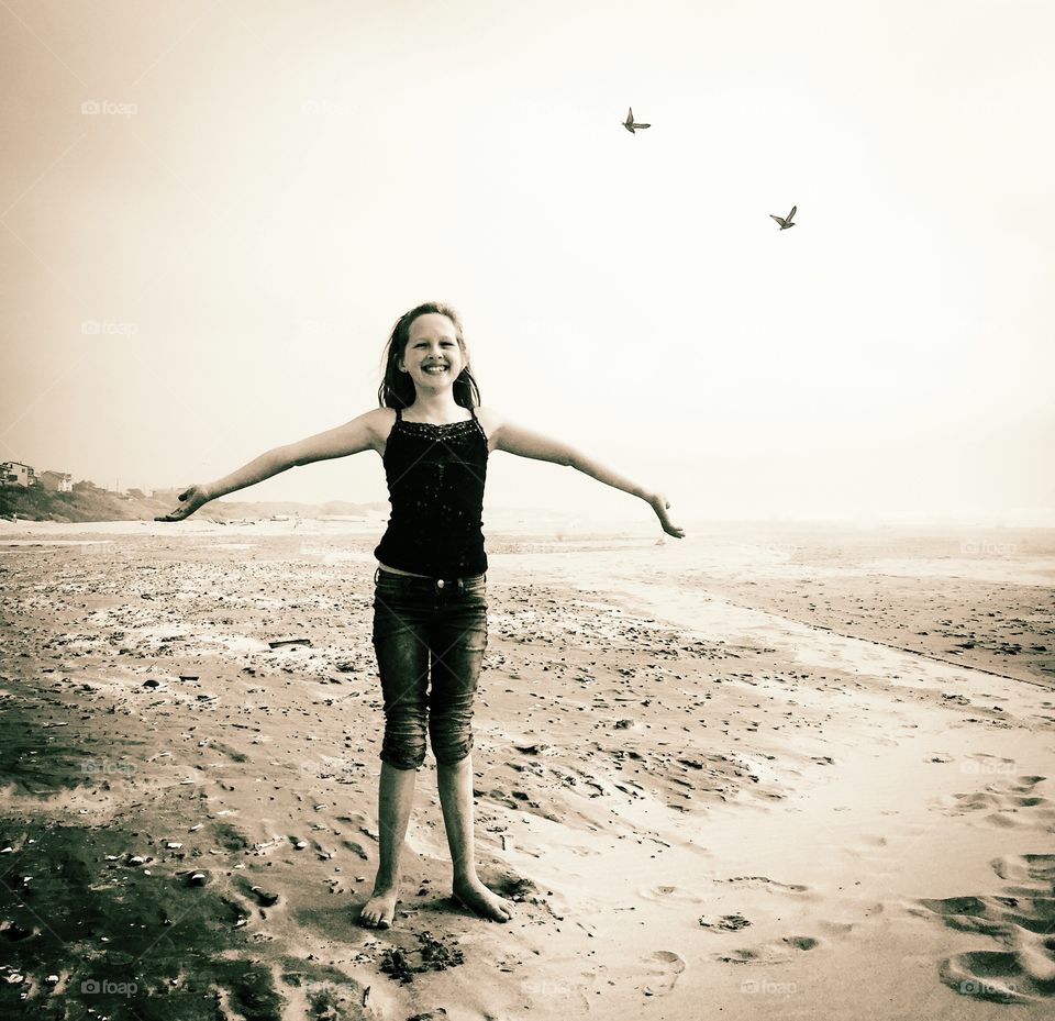 Teenage girl stretching arm at beach