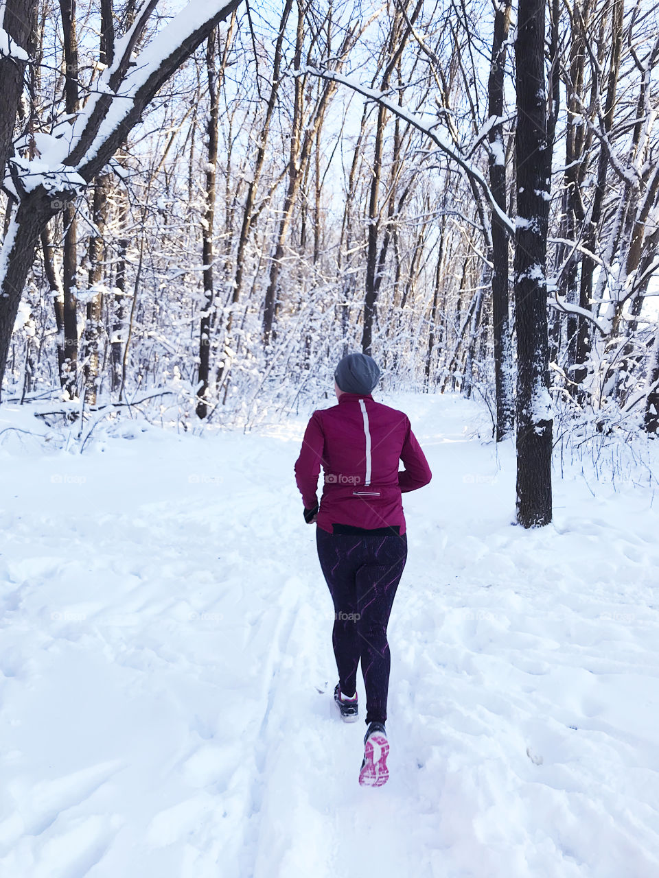 Young woman starting a new year with a losing weight and running through the snowy forest in January 