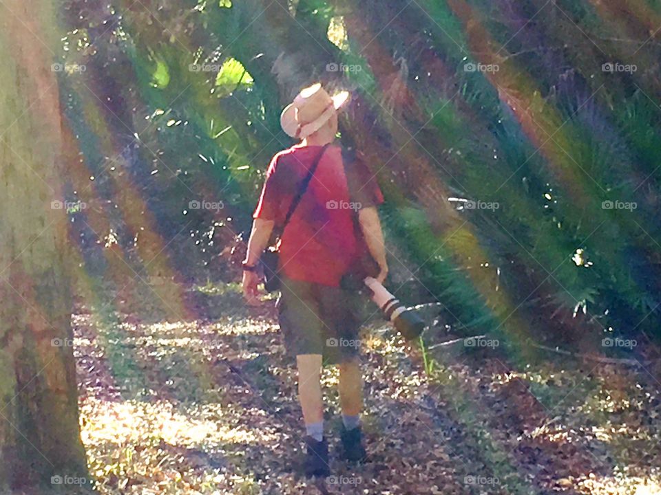 Photographer in nature walking through a rainbow of sunbeams.
