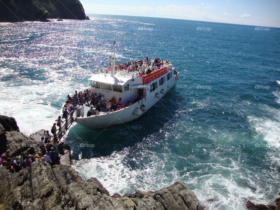 people or tourists boarding a small cruise ship at Cinque Terre, Italy in a bright sunny day