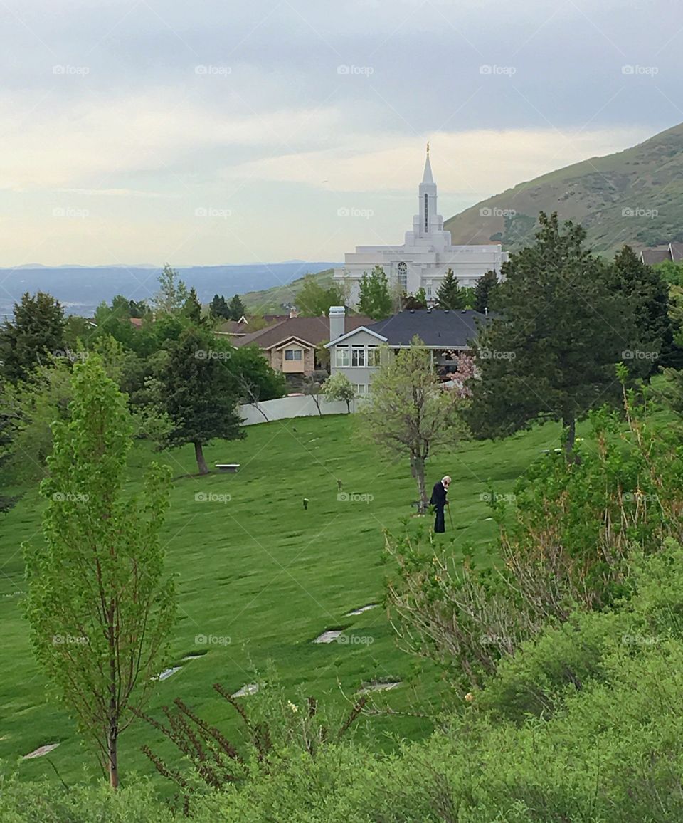 An elderly man paying his respects at a cemetery gravesite near the Mormon Church in Bountiful, Utah. 