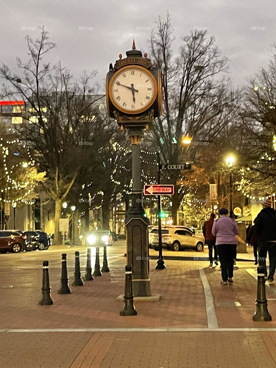 Charming street scene with an old-fashioned clock in downtown Greenville, SC. The clock is framed by the hustle and bustle near Main Street, with quaint buildings and local shops in the background.