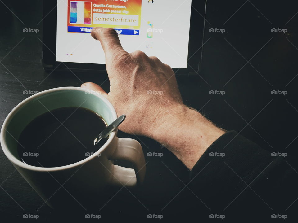 Man using a tablet while drinking coffee