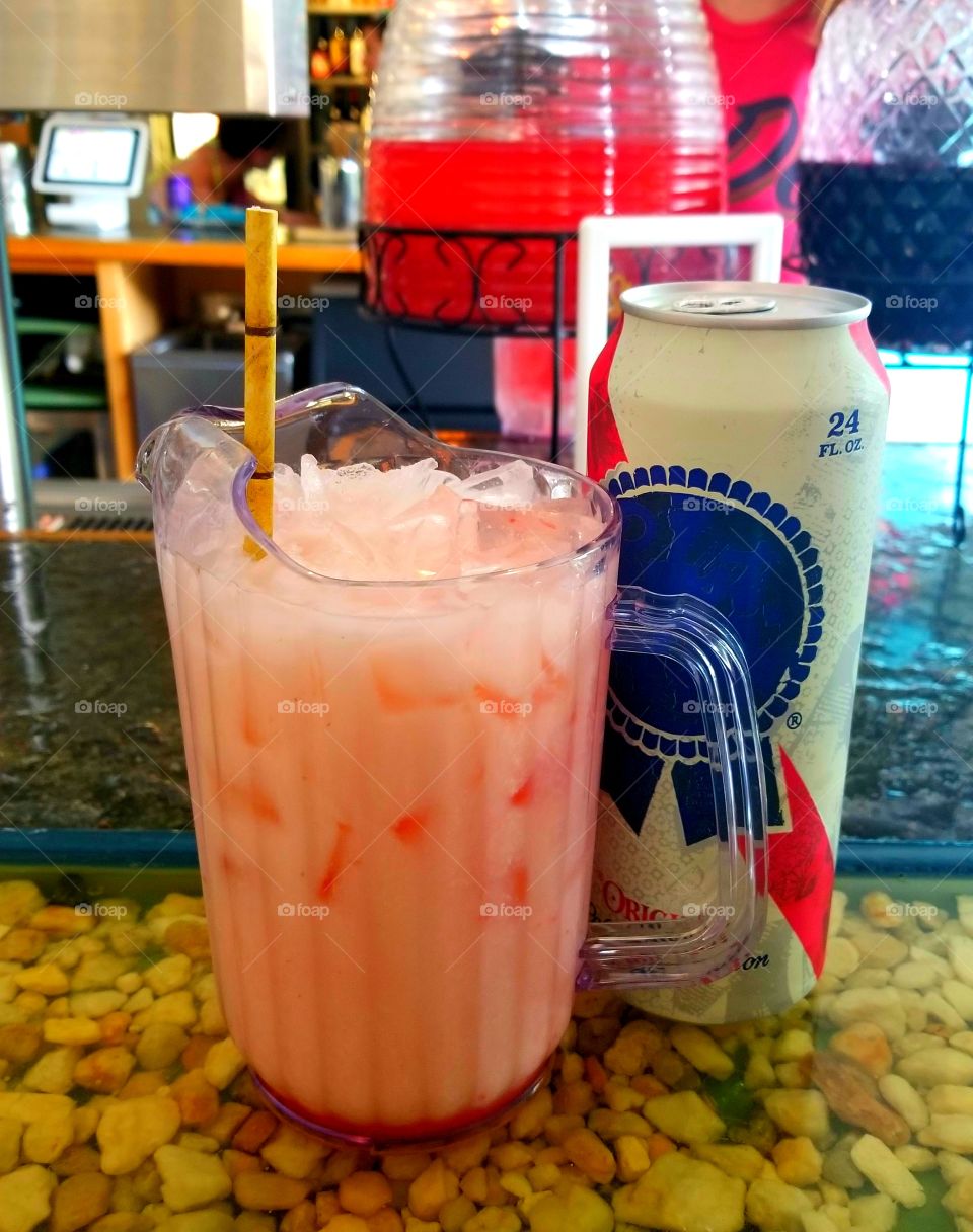 Full iced pitcher of Summer goodness with strawberry pina colada complete with tiki straw and cold PBR can of beer.