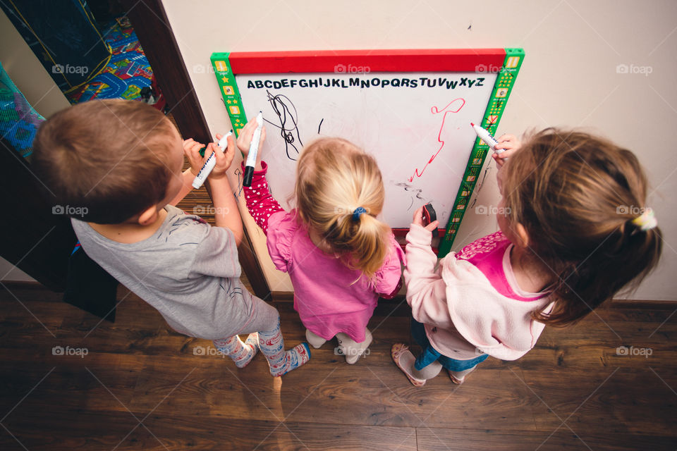 Children drawing a pictures learning a letters playing together using whiteboard and markers