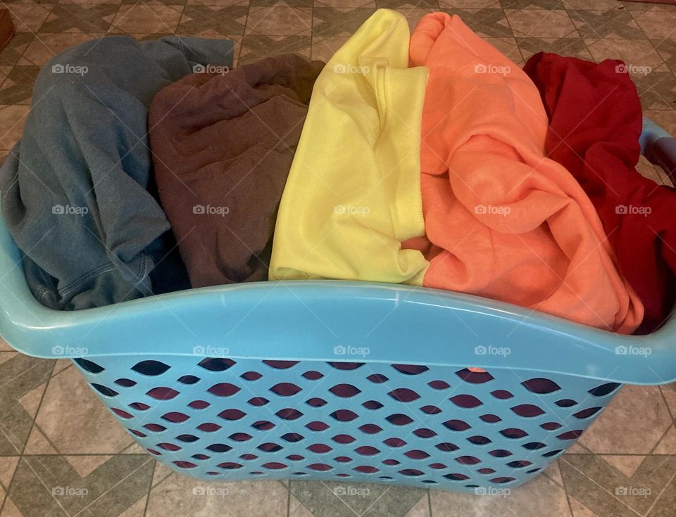 A full laundry, basket of clothes, displaying all the colors of fall all ready to go on the wash.