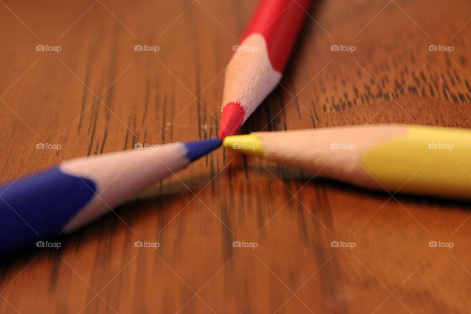 This is a up close picture of the primary colors of pencils on a wood table.