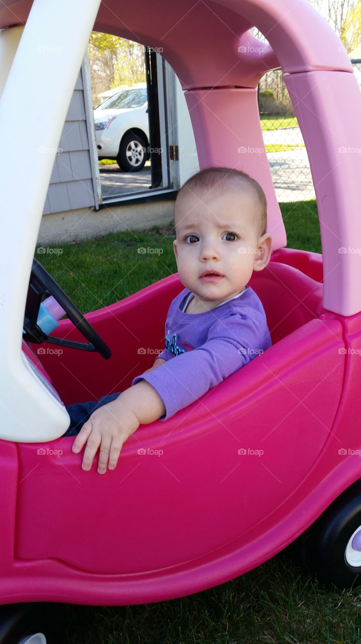 infant girl in toy car outside