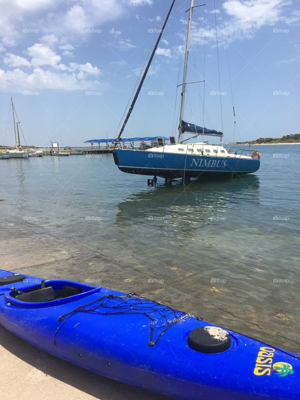 Blue sea kayak and sailboat in little harbor 